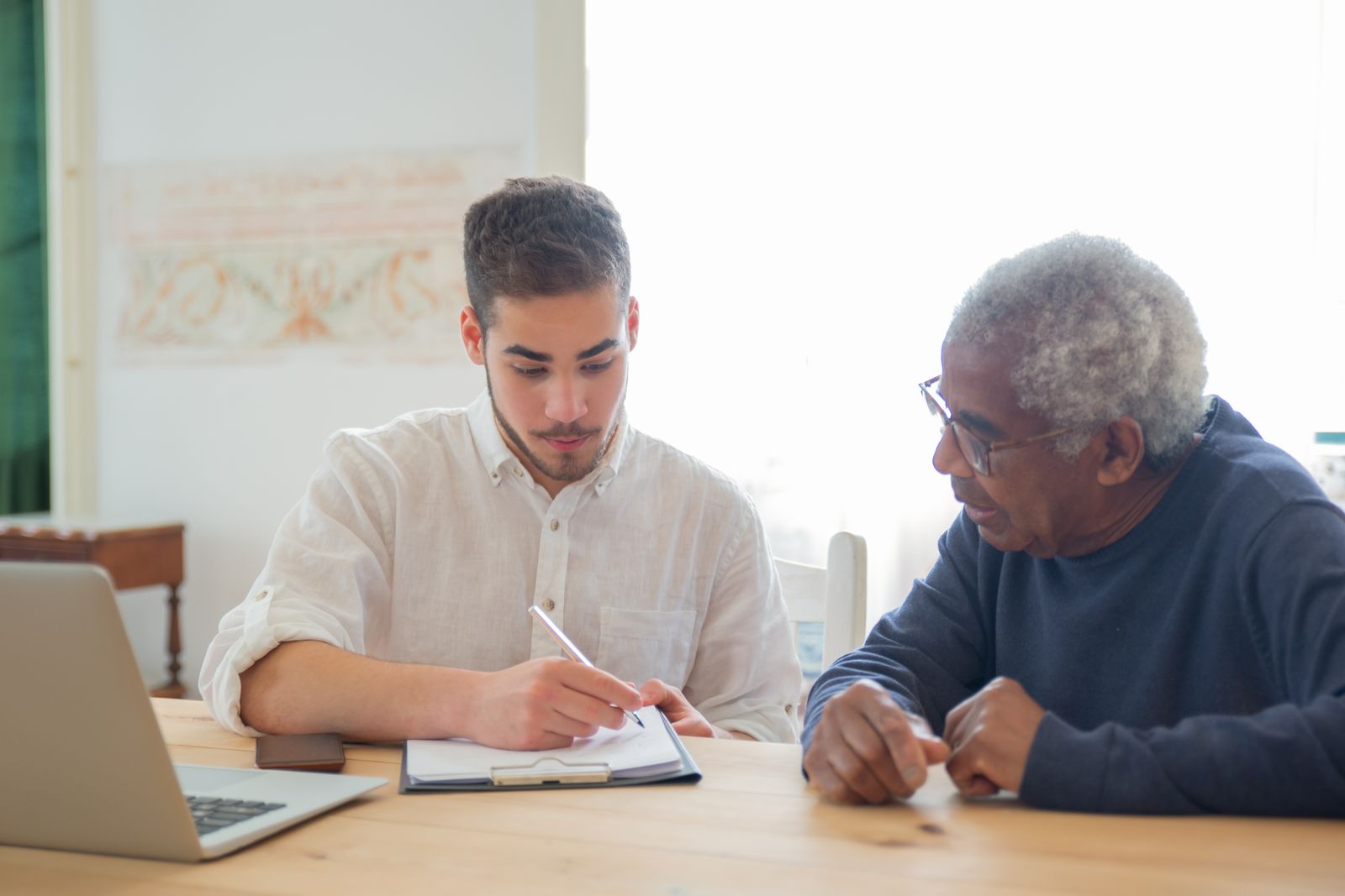 Specialist reviewing paperwork with an elderly man at a table